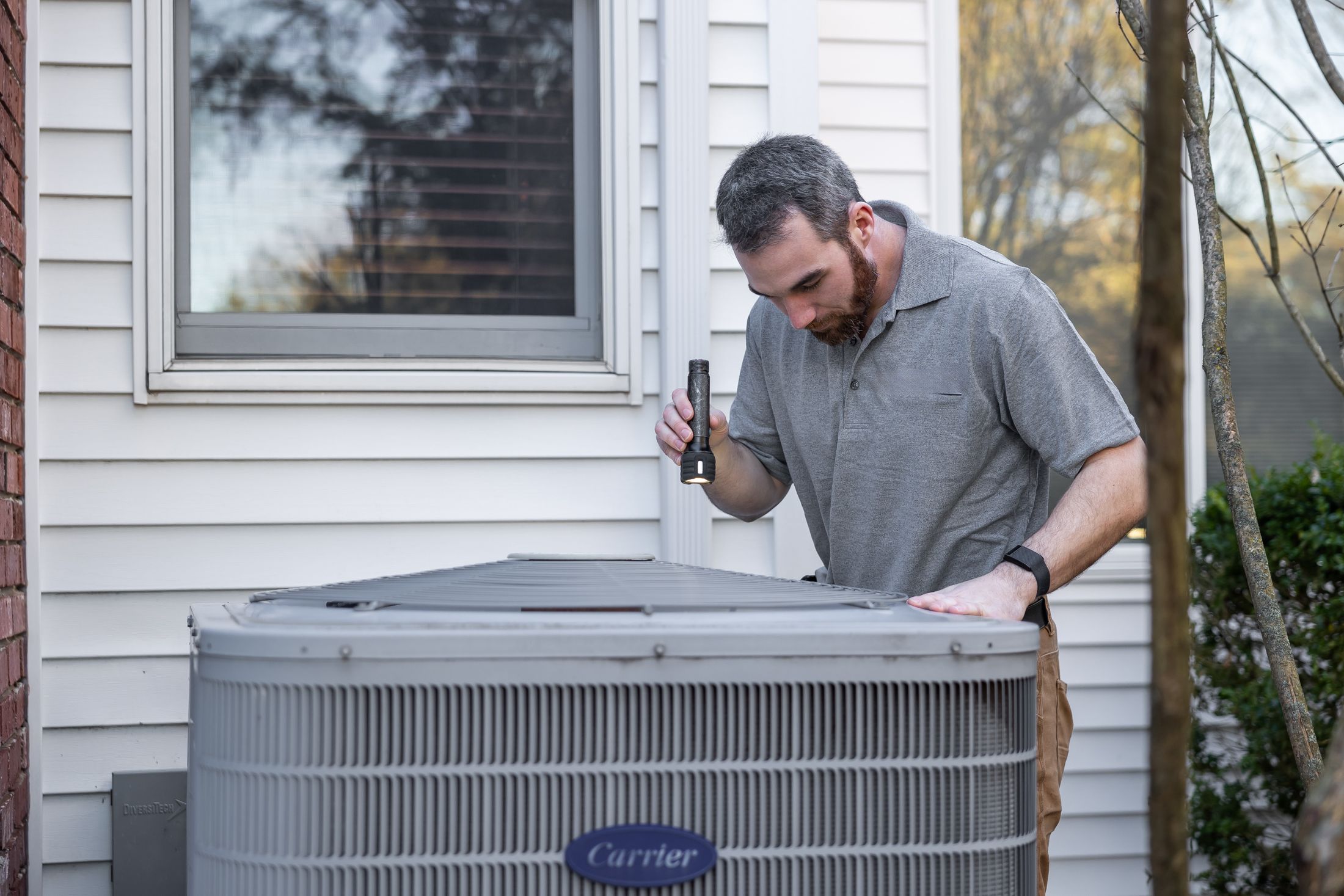 Technician inspecting an outdoor heating and cooling unit