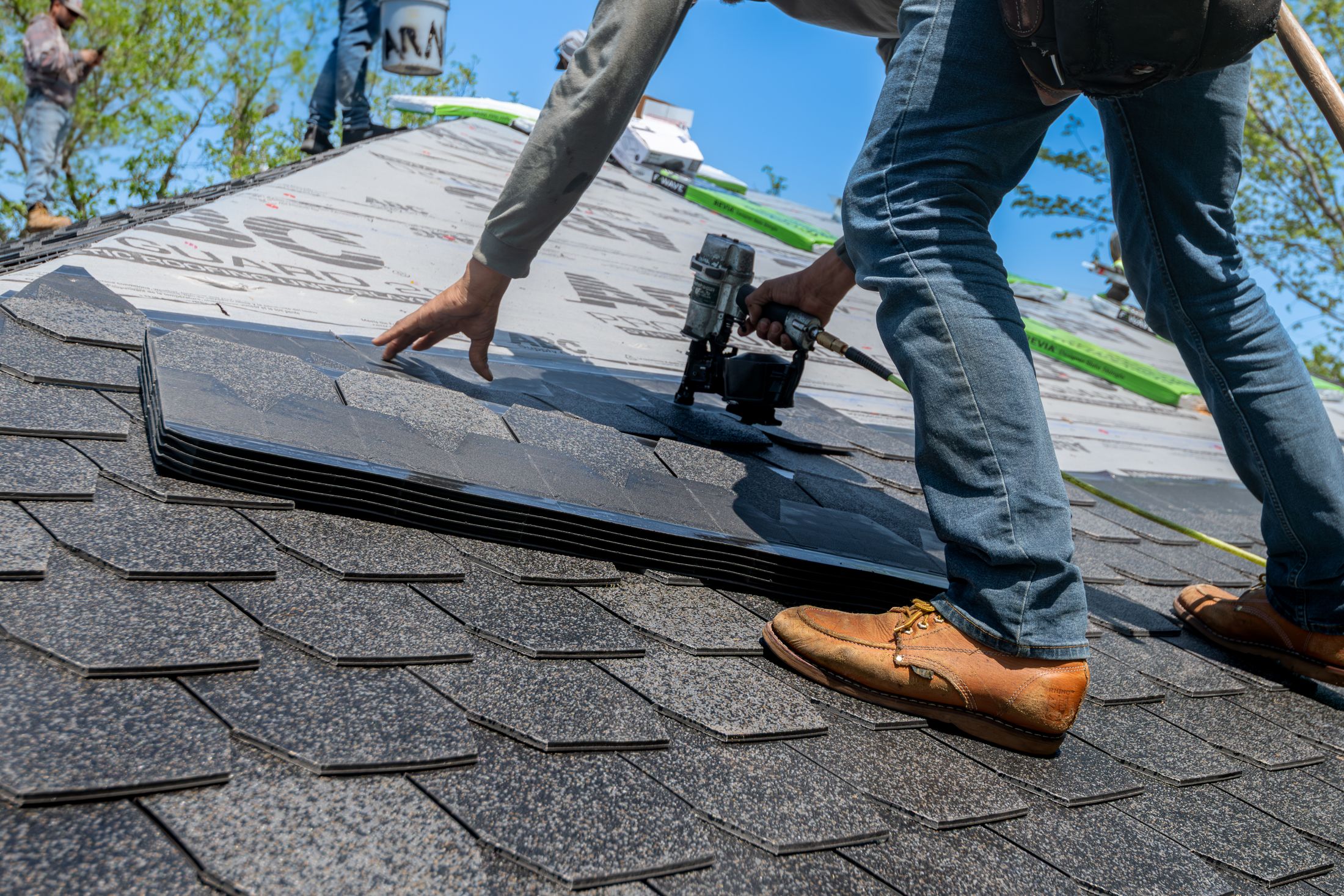 Roofer installing shingles on a residential roof